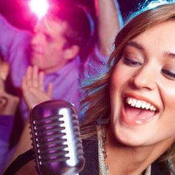 Frau singt auf einem Event Karaoke in ein altmodisches Mikrofon